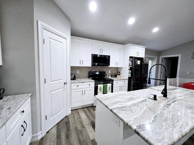 kitchen with light stone counters, a center island, white cabinets, and black appliances