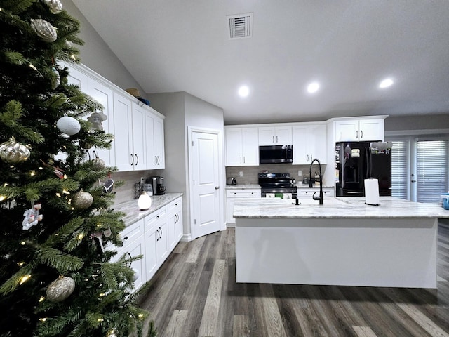 kitchen with backsplash, black appliances, white cabinets, an island with sink, and light stone counters