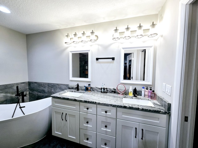 bathroom with vanity, a bath, and a textured ceiling