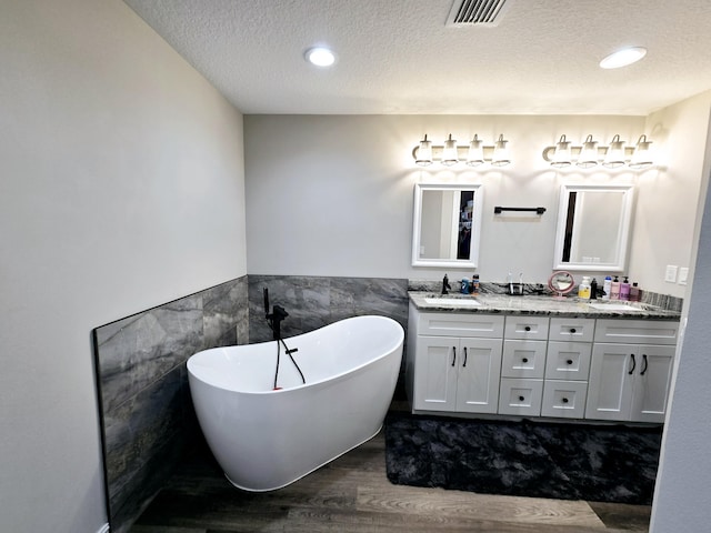 bathroom featuring vanity, a bath, a textured ceiling, and wood-type flooring