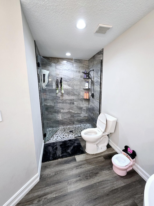 bathroom with a tile shower, a textured ceiling, and toilet