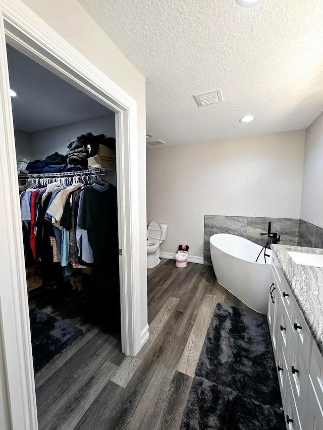 bathroom featuring a bathtub, wood-type flooring, a textured ceiling, and a bidet