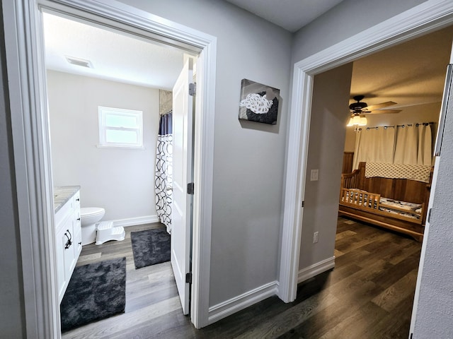 bathroom featuring ceiling fan, vanity, wood-type flooring, and toilet