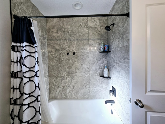 bathroom with shower / bathtub combination with curtain and a textured ceiling