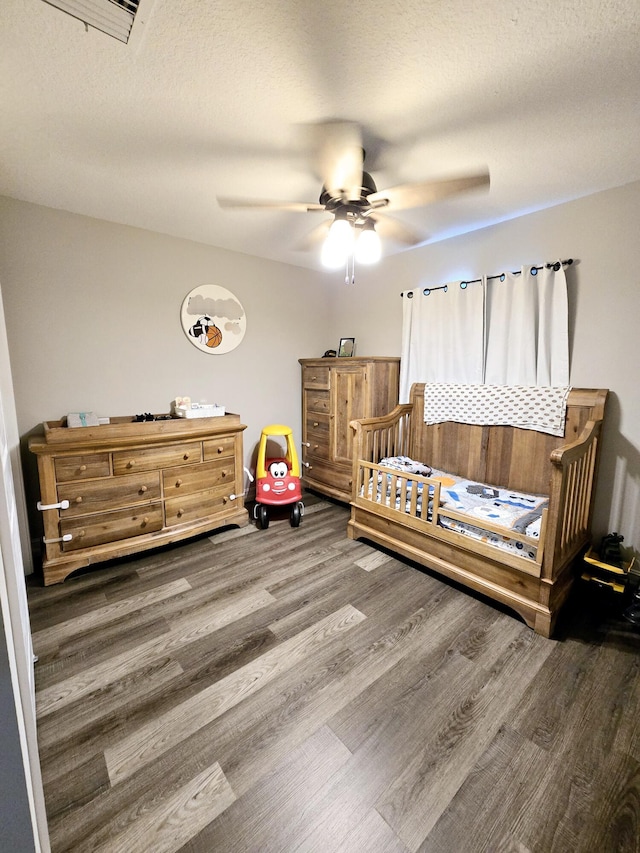 bedroom with a textured ceiling, ceiling fan, and dark hardwood / wood-style floors