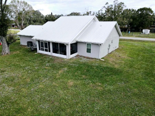 back of property with a sunroom, a yard, and cooling unit