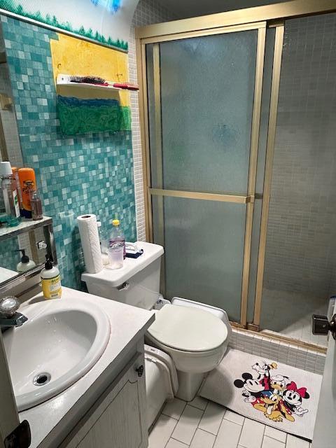 bathroom with tile patterned flooring, vanity, toilet, and an enclosed shower