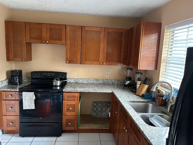 kitchen with light stone counters, a textured ceiling, sink, light tile patterned floors, and electric range