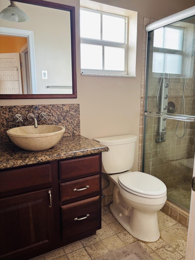 bathroom with backsplash, toilet, an enclosed shower, and a healthy amount of sunlight