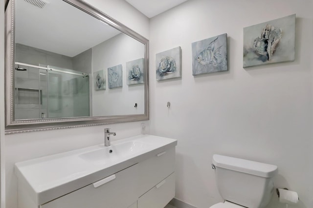 bathroom with vanity, toilet, and a shower with shower door