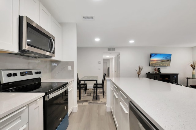 kitchen featuring light hardwood / wood-style floors, light stone countertops, white cabinetry, and stainless steel appliances