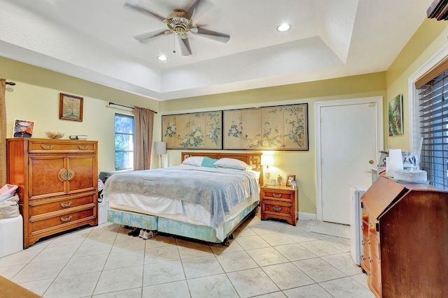 bedroom featuring ceiling fan, light tile patterned floors, and a raised ceiling