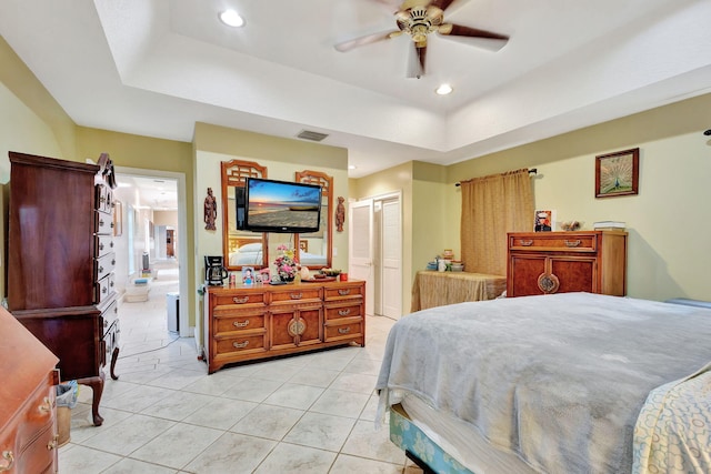 bedroom with a tray ceiling, ceiling fan, a closet, and connected bathroom