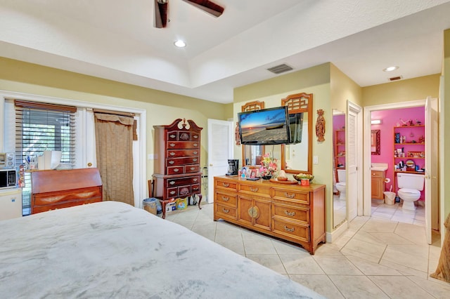 bedroom with ensuite bathroom, light tile patterned flooring, and ceiling fan