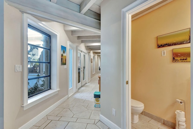 corridor featuring light tile patterned floors and beamed ceiling