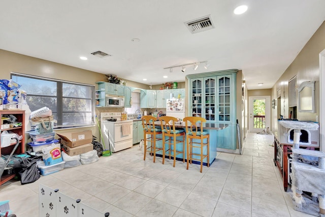 kitchen with white appliances, light tile patterned floors, and a breakfast bar area