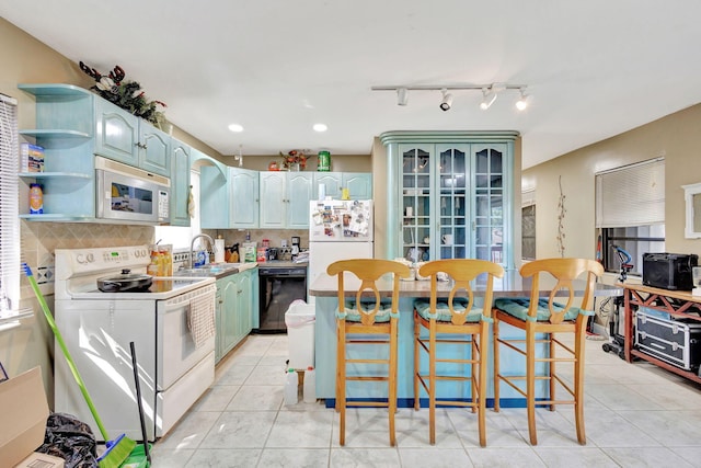 kitchen featuring white appliances, sink, a kitchen island, and a breakfast bar area