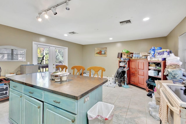 kitchen with french doors, a kitchen island, rail lighting, and light tile patterned floors