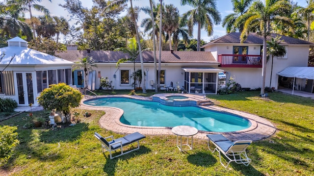 back of property featuring a lawn, french doors, an in ground hot tub, a balcony, and a sunroom