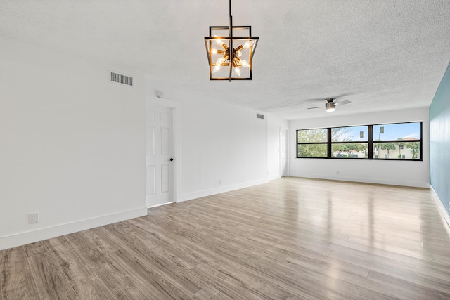 unfurnished living room featuring a textured ceiling, ceiling fan with notable chandelier, and light wood-type flooring