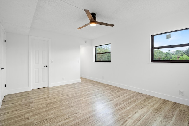 spare room featuring a textured ceiling, light wood-type flooring, and ceiling fan