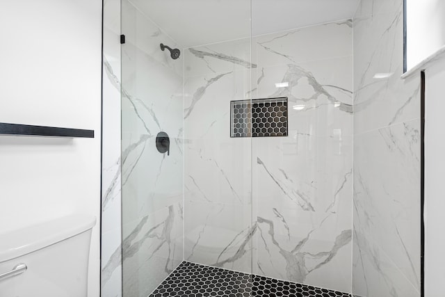 bathroom with a tile shower and toilet