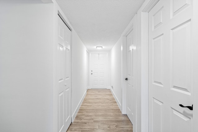 hallway featuring a textured ceiling and light hardwood / wood-style flooring