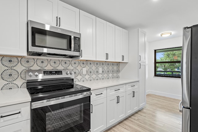 kitchen with decorative backsplash, white cabinets, stainless steel appliances, and light wood-type flooring