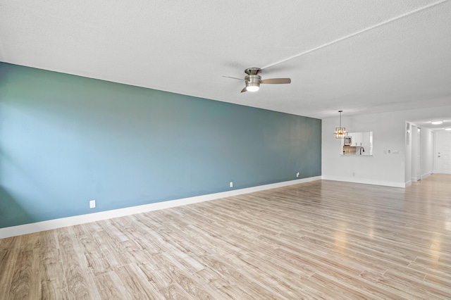 unfurnished living room featuring a textured ceiling, ceiling fan with notable chandelier, and light wood-type flooring