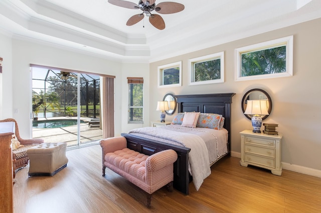 bedroom featuring crown molding, access to outside, light hardwood / wood-style floors, and a tray ceiling