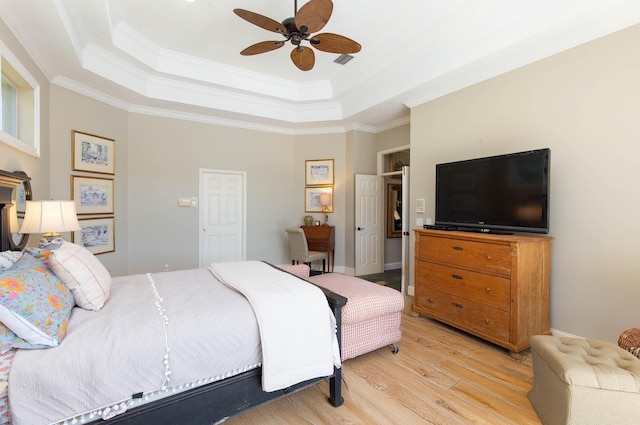 bedroom featuring a raised ceiling, ornamental molding, and light hardwood / wood-style floors