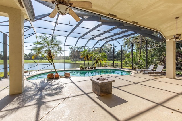 view of swimming pool featuring a patio area, a water view, and glass enclosure