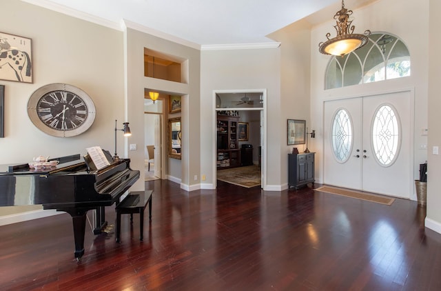 foyer with crown molding, a towering ceiling, dark hardwood / wood-style flooring, and french doors