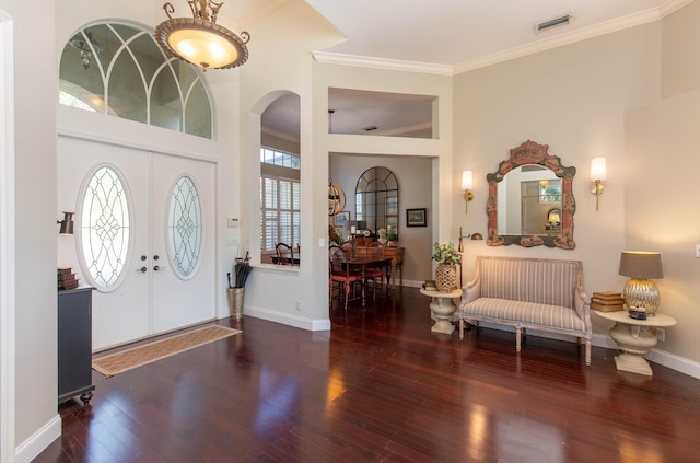 entrance foyer with ornamental molding, dark wood-type flooring, and french doors