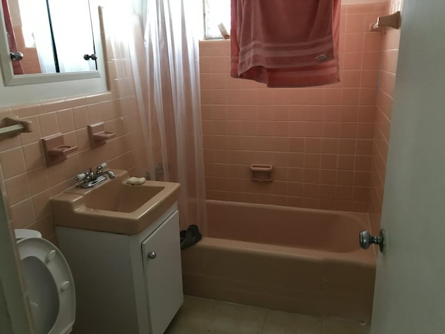 full bathroom featuring shower / bath combo, vanity, tile patterned flooring, toilet, and tile walls