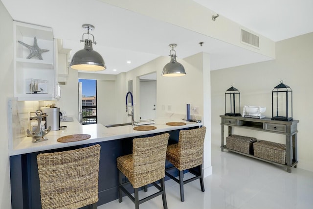 kitchen with kitchen peninsula, a kitchen breakfast bar, sink, pendant lighting, and white cabinets