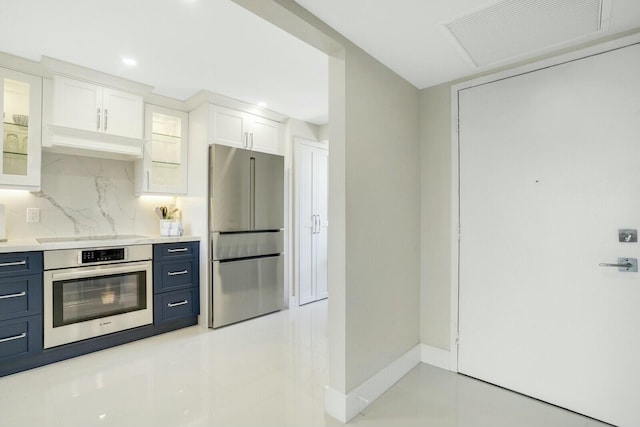 kitchen featuring blue cabinetry, stainless steel appliances, white cabinetry, and tasteful backsplash