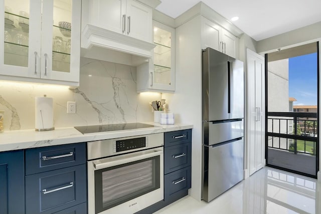 kitchen with backsplash, white cabinetry, blue cabinets, and appliances with stainless steel finishes