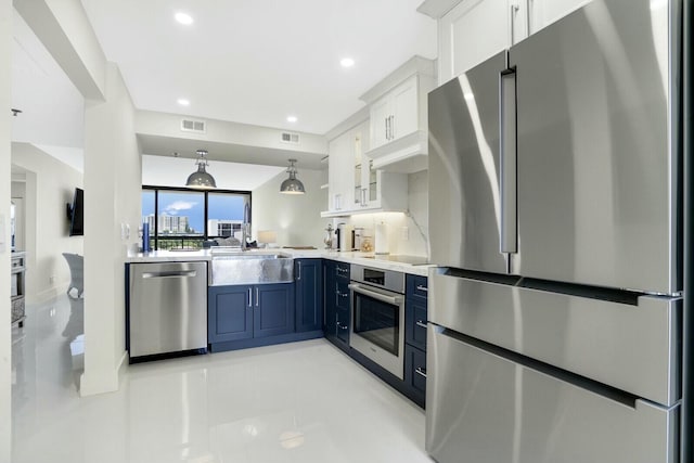 kitchen featuring blue cabinetry, sink, stainless steel appliances, pendant lighting, and white cabinets