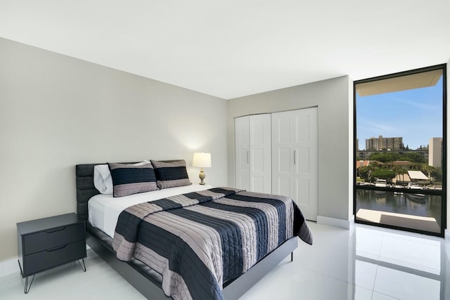 tiled bedroom with access to outside, floor to ceiling windows, and a closet