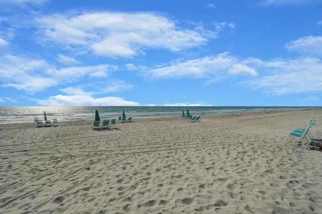 view of property's community featuring a water view and a beach view