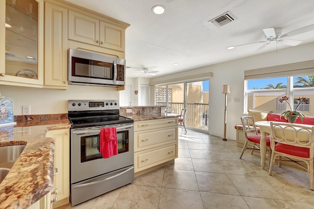 kitchen with cream cabinetry, appliances with stainless steel finishes, and stone countertops