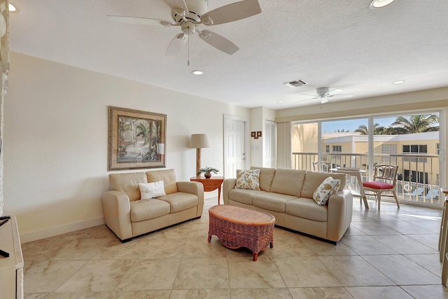 living room with ceiling fan and a textured ceiling