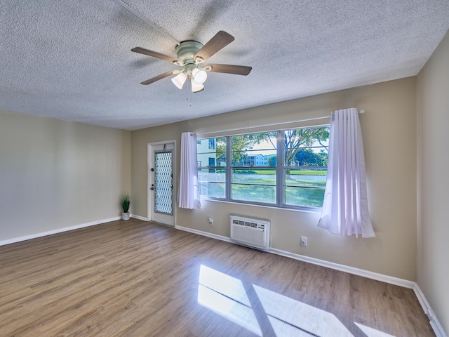 unfurnished room featuring a wall unit AC, ceiling fan, light hardwood / wood-style floors, and a textured ceiling