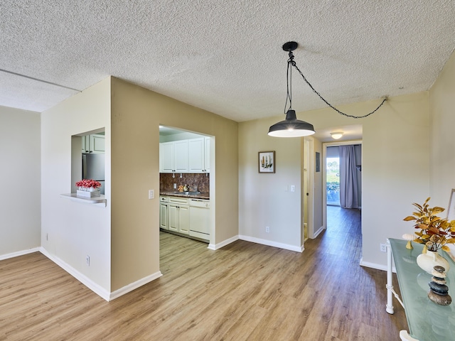 unfurnished dining area featuring a textured ceiling and light wood-type flooring