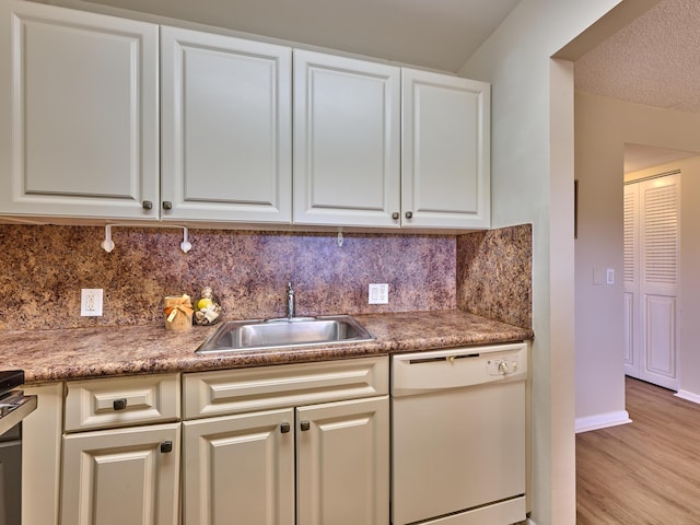 kitchen featuring backsplash, sink, dishwasher, light hardwood / wood-style floors, and white cabinetry