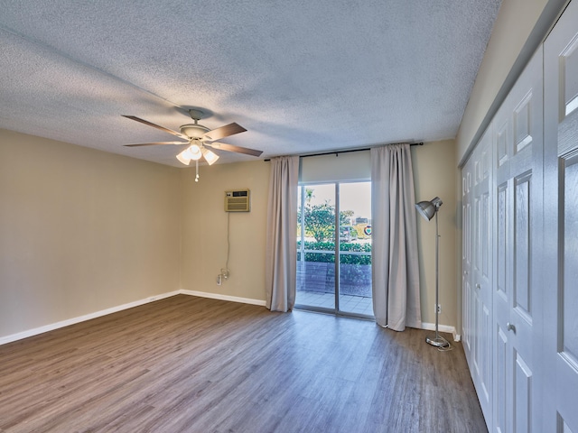 empty room featuring an AC wall unit, ceiling fan, a textured ceiling, and hardwood / wood-style flooring