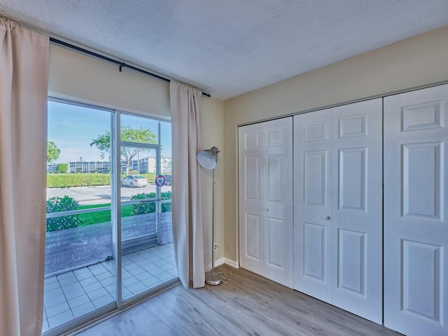 doorway with light hardwood / wood-style flooring and a textured ceiling