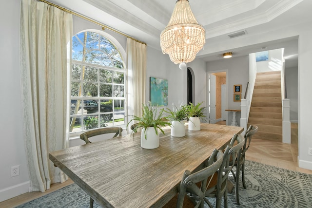 dining space with crown molding, a tray ceiling, and an inviting chandelier