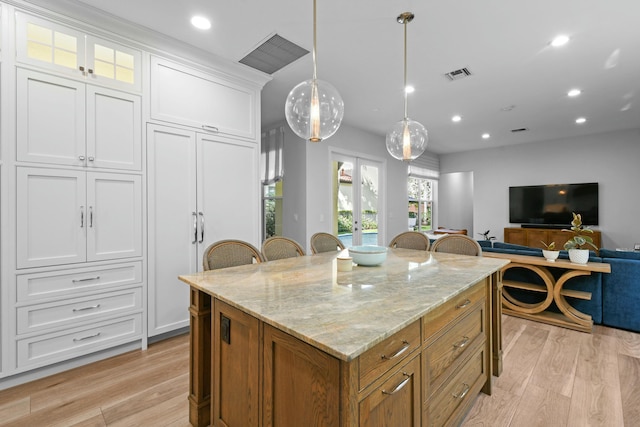 kitchen featuring french doors, white cabinetry, a center island, hanging light fixtures, and light wood-type flooring